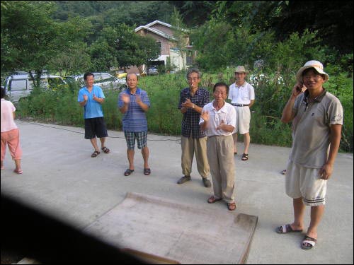 동네 사람들이 완성된 정자를 보고 박수를 치는 모습들 